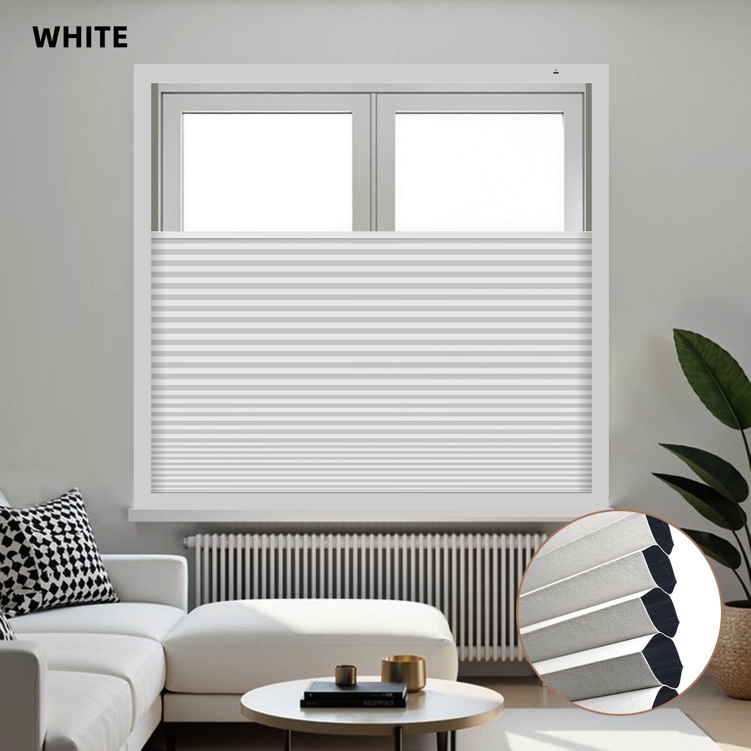 White blackout honeycomb shades covering a window in a living room with a white sofa and decorative items.