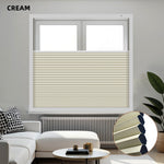 Cream-colored blackout honeycomb shades on a window with a modern living room setting.