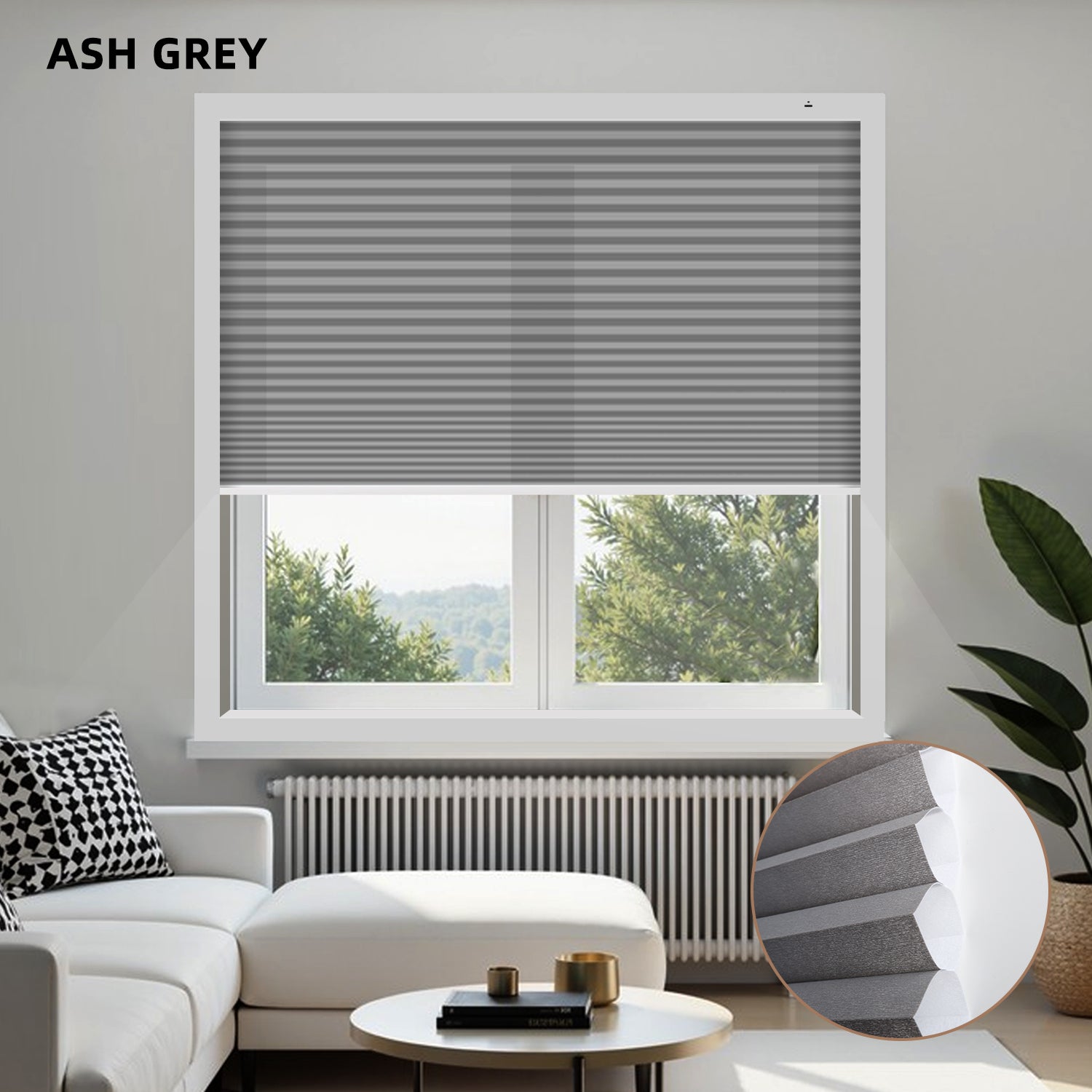 Living room with ash grey light filtering honeycomb shades, white sofa, and a window view.