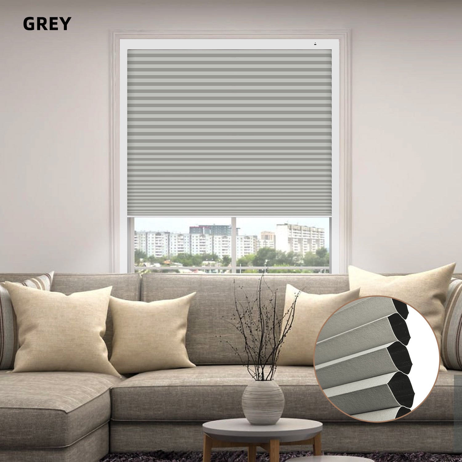 Gray custom size cellular shades in a window with a gray sofa and decorative elements.

