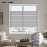 Window with white gray light filtering cellular blinds in a room with furniture and decor.